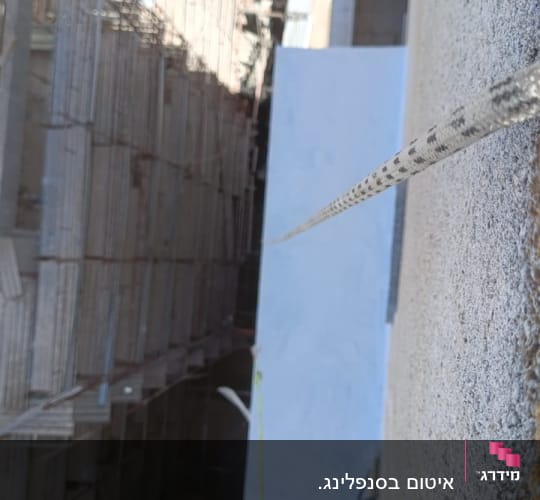 חבל תלוי מגובה לצד קיר בניין בבנייה
